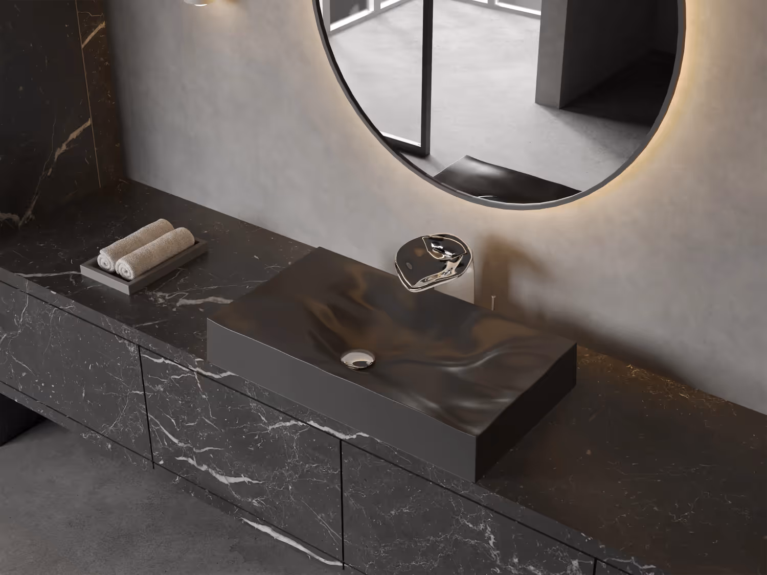 Dune black wall-hung wash basin on a marble vanity below a round backlit mirror