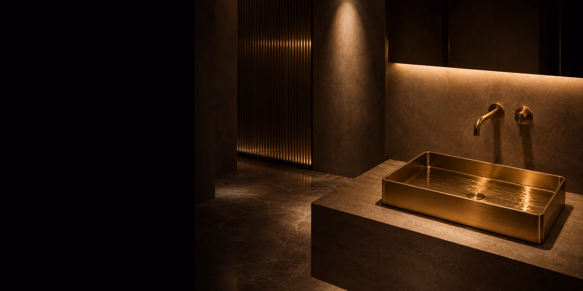 Inox brass rectangular countertop basin with wall mixer in a dimly lit stone bathroom