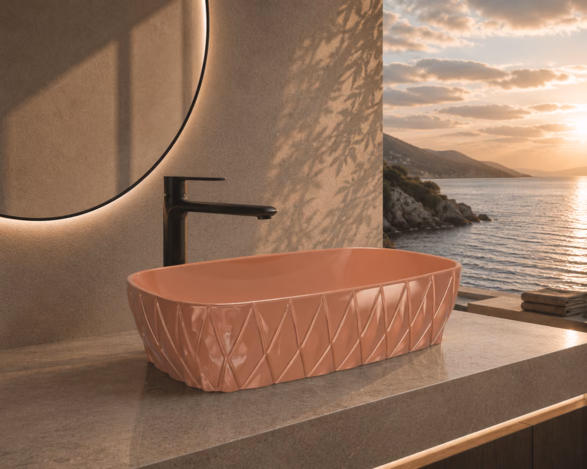 Blush pink faceted countertop wash basin with black tap and round mirror overlooking the sea