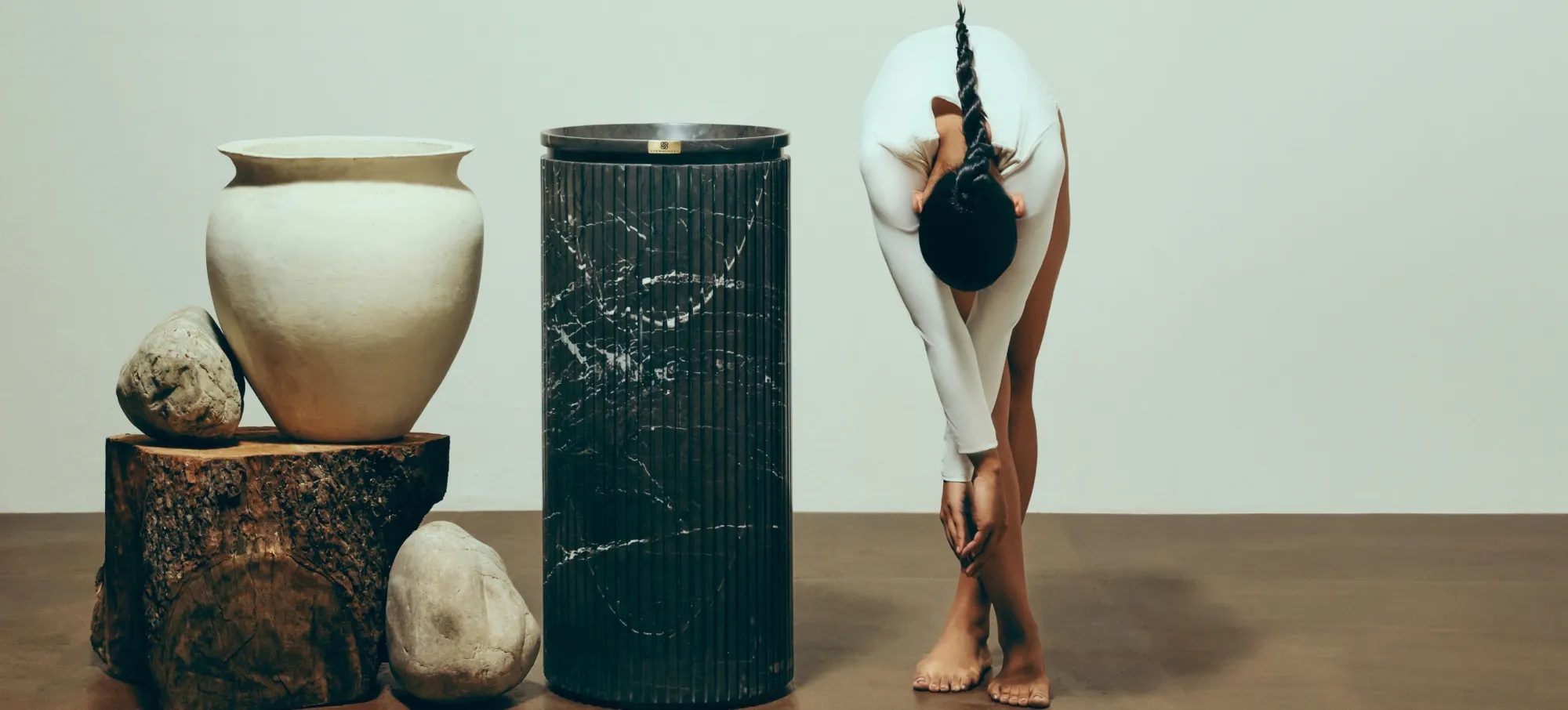 An Ode to Germany: a dancer beside a fluted black marble basin pedestal and a pale clay vase