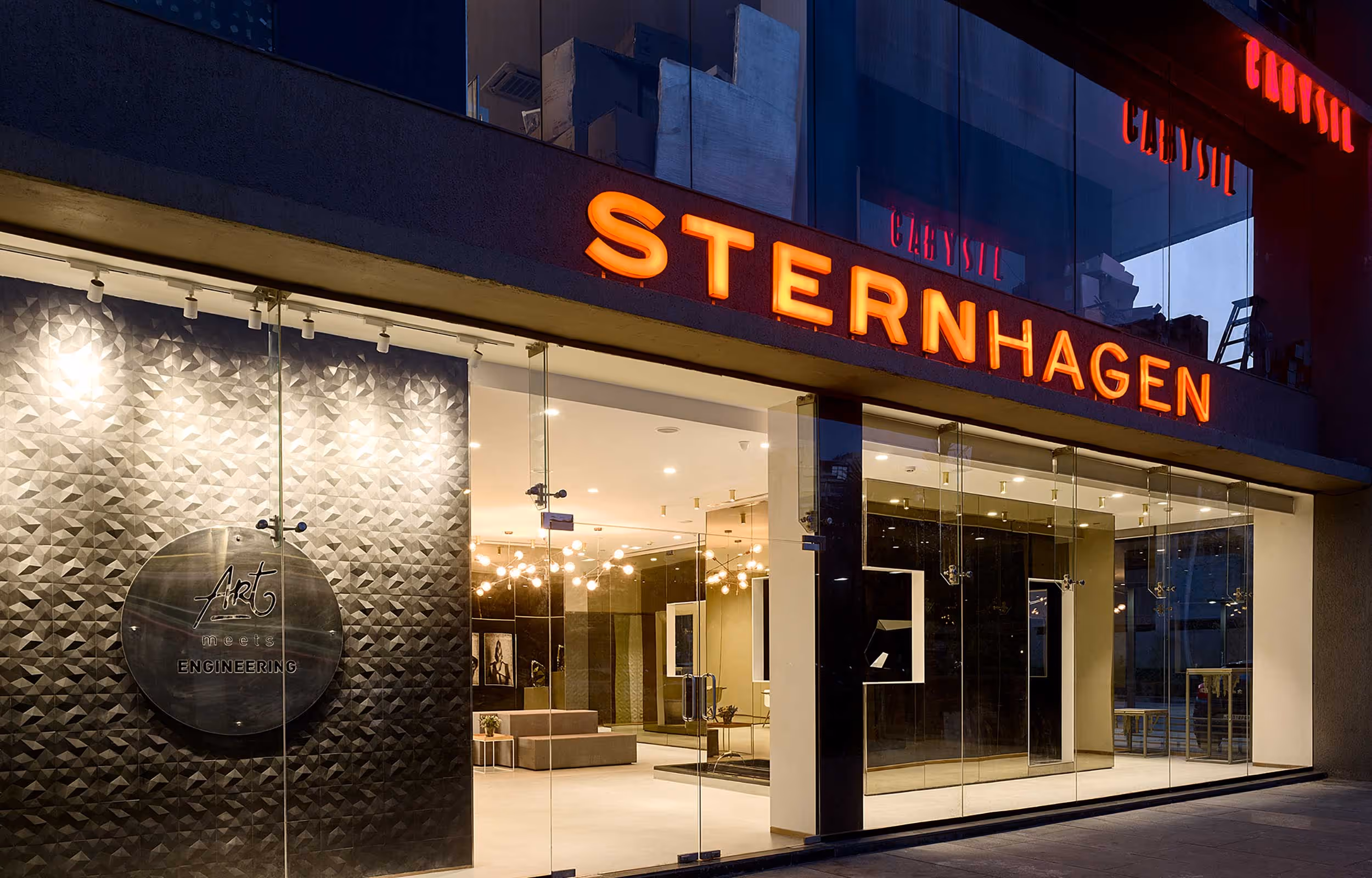 Sternhagen showroom storefront at night with illuminated wordmark sign and glass facade